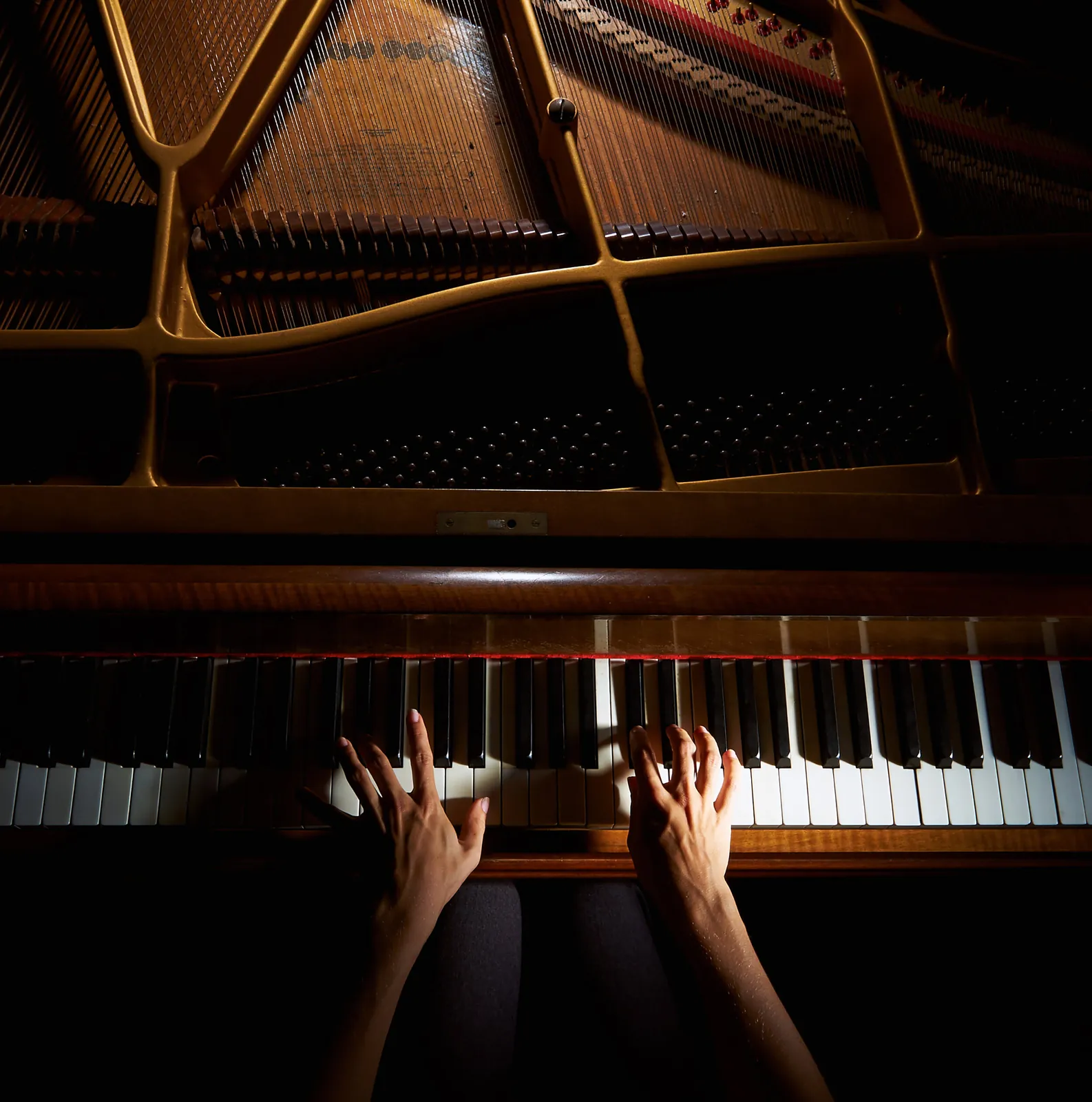 Mains d’une pianiste vues depuis l’intérieur d’un piano à queue